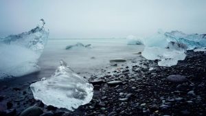 chucks of ice on a pebbled wintery beach - imagery for "Considerations" by Laurinda Lind