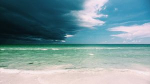 A pristine beach with darkening sky - imagery for "Why We Went to Florida" by Glen Sorestad